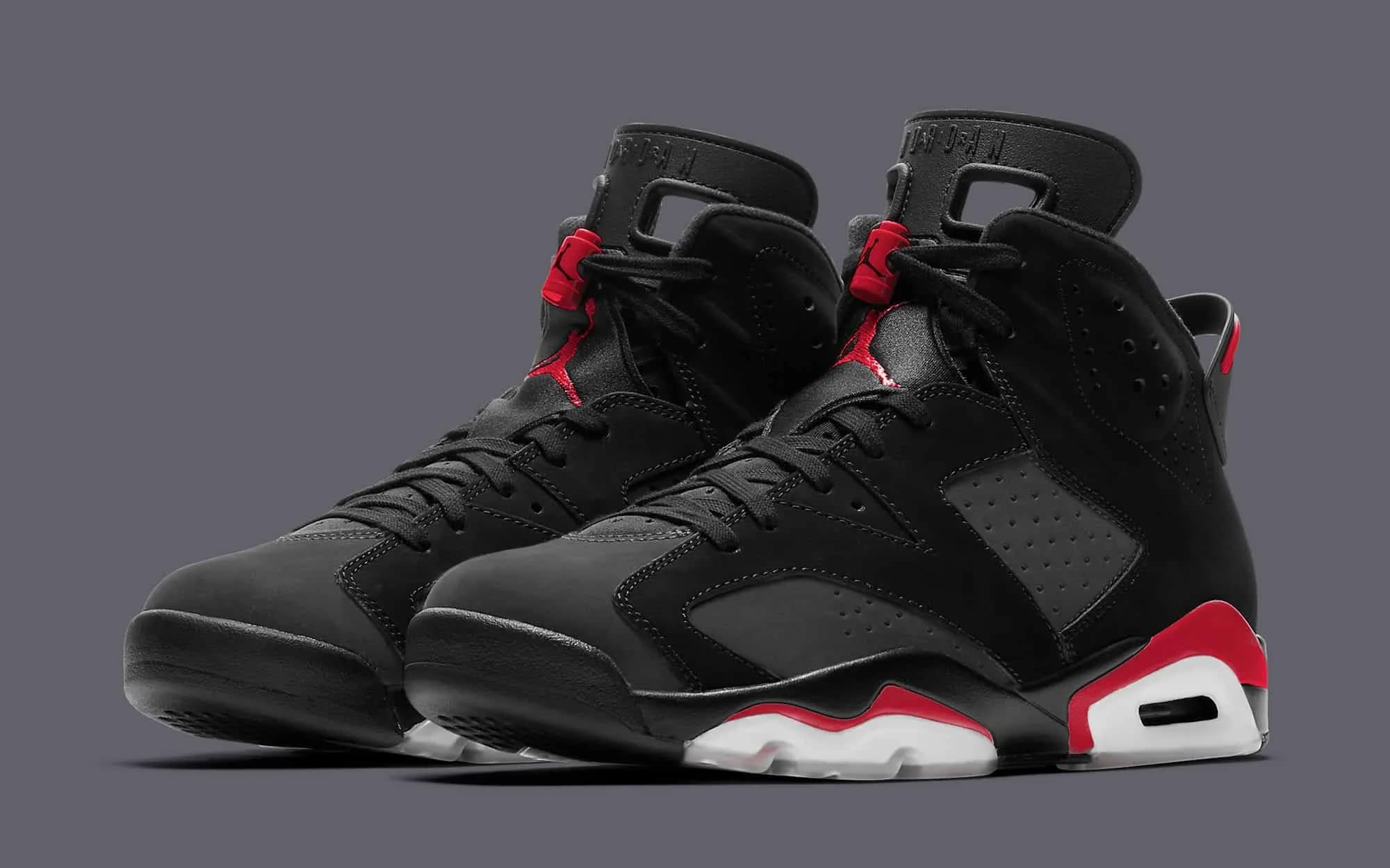Pair of black and red sneakers featuring perforated design and visible air sole units, showcased against a dark gray background.