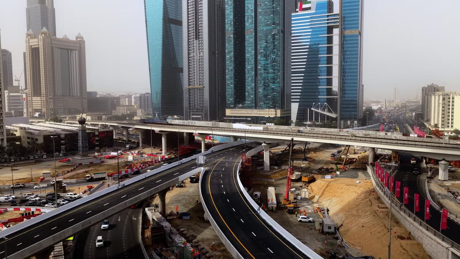 Aerial view of a busy urban construction site with overpasses, surrounded by tall modern skyscrapers.